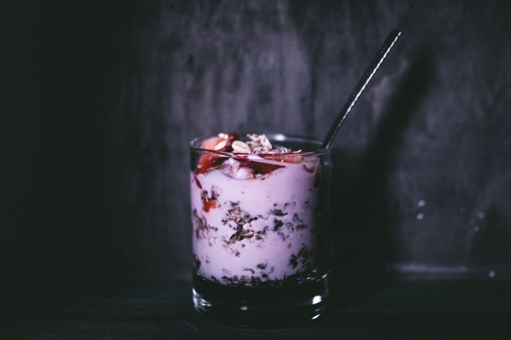 Pahare cu straturi de iaurt grecesc, fructe de pădure și granola, așezate pe o masă luminoasă