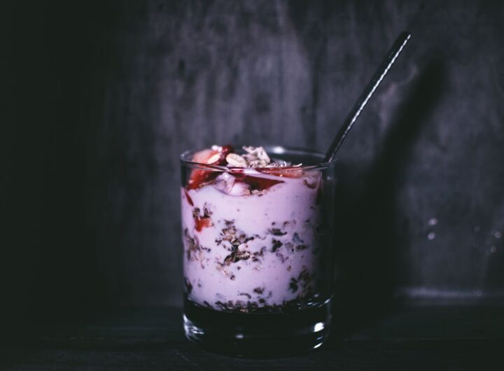 Pahare cu straturi de iaurt grecesc, fructe de pădure și granola, așezate pe o masă luminoasă