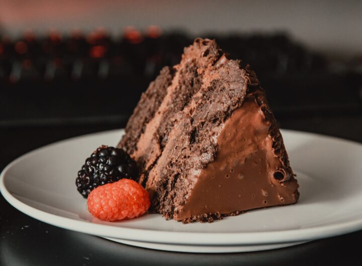 Felie de tort de ciocolată cu straturi de blat de cacao și cremă, acoperită cu glazură lucioasă